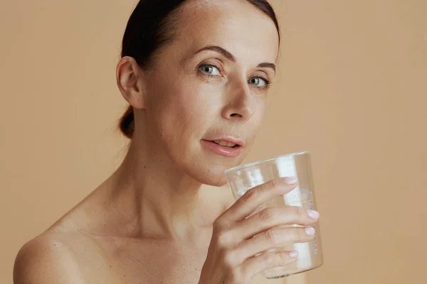 Modern Vrouwtje Met Glas Water Geïsoleerd Beige Achtergrond — Stockfoto