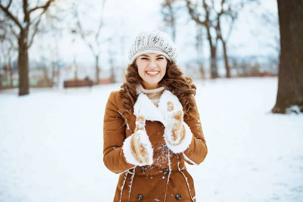 一个快乐的现代女人 冬天的时候 她带着手套 头戴针织的帽子 披着羊皮外套 站在城市公园外面 — 图库照片