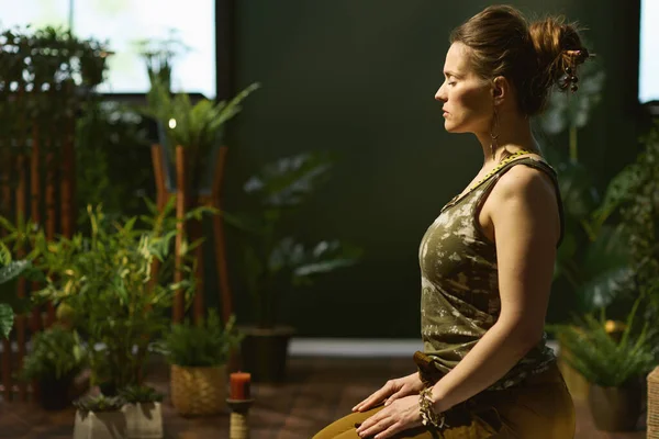 modern middle aged woman in the modern green living room stretching.