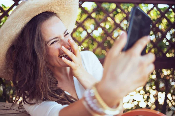 Beyaz Tişörtlü Şapkalı Yaşında Bir Kadın Terasta Akıllı Bir Telefonla — Stok fotoğraf