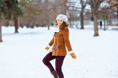 Kış aylarında şehir parkında örgü şapkalı ve koyun derisi ceketli mutlu stil sahibi bir kadın..