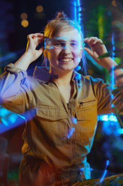 Oyuncak tabancası ve sanal gerçeklikte fütürist gözlükleriyle gülümseyen modern çocuk..