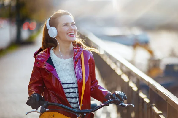 Счастливая Современная Женщина Красном Дождевике Велосипедом Наушниками Улице Городе — стоковое фото