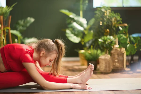 Młoda Kobieta Czerwonym Stroju Fitness Nowoczesnym Zielonym Salonie Uprawia Jogę — Zdjęcie stockowe