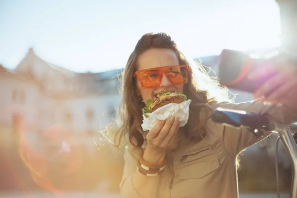 Güneş Gözlüklü Motosikletli Sandviçli Akıllı Telefonlu Mutlu Genç Bir Kadın — Stok fotoğraf