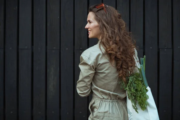 Glückliche Moderne Frau Overall Mit Tragetasche Gegen Schwarze Holzwand Draußen — Stockfoto