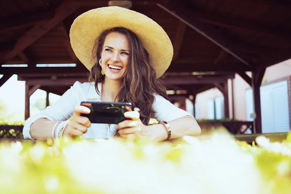 Smiling Modern Middle Aged Woman White Shirt Hat Using Smartphone — Foto Stock