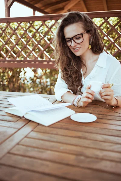 Relaxed Trendy Female White Shirt Eyeglasses Sitting Table Drinking Coffee — 图库照片