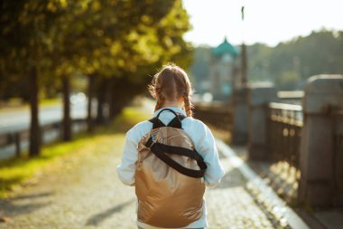 Beyaz tişörtlü ve sırt çantalı modaya uygun bir öğrencinin şehirdeki açık havada okula gidişini gördüm..