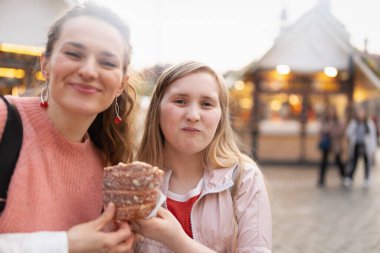 Mutlu modern anne ve çocuk şehirdeki panayırda trdelnik yiyor..