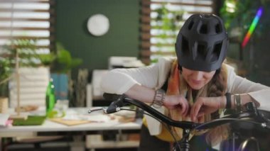 Portrait of stylish 40 years old business woman in bike helmet with bicycle in modern eco office.