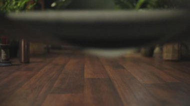 Closeup on middle aged woman with yoga mat folding mat in the green living room.