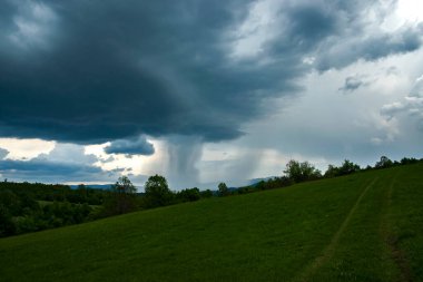 Yağmur sırasında dramatik fırtınalı bulutlarla kaplı dağ manzarası