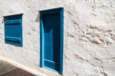 White old vintage house facade with blue wooden door and window shutters