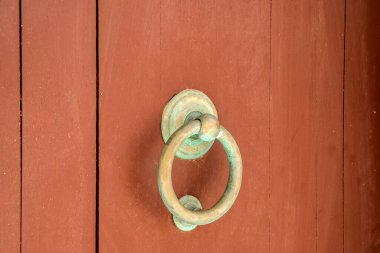 Ring knocker on wooden front brown door closeup