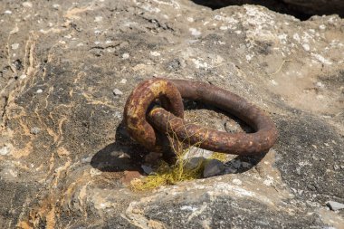 Old weathered rusty ring for tying boats closeup on pier