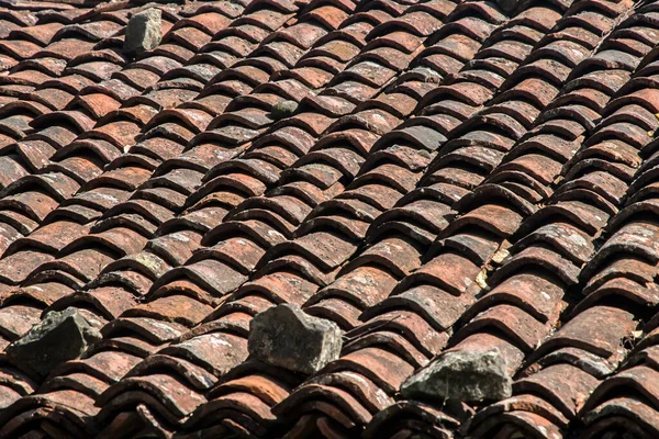 Yıpranmış kil kiremitlerden eski kır evinin çatısına yakın.