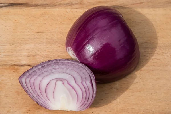 Fresh red onion and cut in half sliced on wooden board background