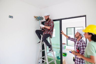İki elektrikçi ve müteahhit inşaat halindeki eve elektrik sistemi kurulmasına yardım ediyor. Bakım servisi Tamir ve Tamirci konsepti