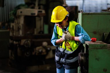 Kalp krizi konsepti. Eski fabrikada göğüs ağrısı çeken siyah mühendis kadın. Metal torna fabrikası.