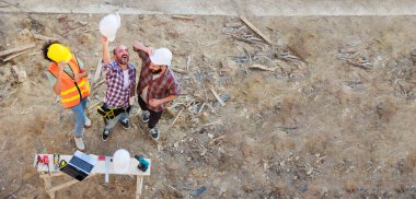 Üst görüntüyü birleştirelim. Başarılı bir takım çalışması birliği. Ev projesinin inşaat alanındaki makine mühendisi ve inşaat ekibi. Eller birleşsin.