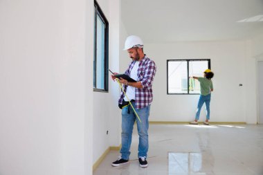 Yeni inşaat alanına pencere döşeyen bir adam. İspanyol inşaat işçisi eldiven ve başlık takıyor.