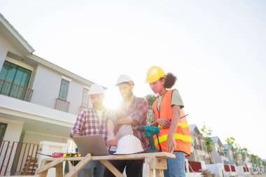 Takım dizüstü bilgisayarda çalışıyor. Profesyonel Makine Mühendisi Ekibi, inşaat sahasının altındaki imalat fabrikasında güvenlik kaskı takıyor..