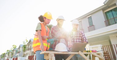 Takım dizüstü bilgisayarda çalışıyor. Profesyonel Makine Mühendisi Ekibi, inşaat sahasının altındaki imalat fabrikasında güvenlik kaskı takıyor..