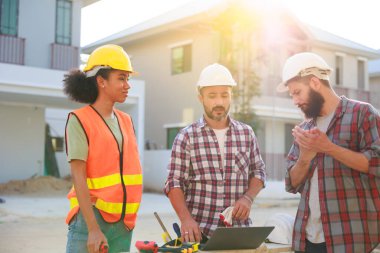 Takım dizüstü bilgisayarda çalışıyor. Profesyonel Makine Mühendisi Ekibi, inşaat sahasının altındaki imalat fabrikasında güvenlik kaskı takıyor..