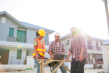 Takım dizüstü bilgisayarda çalışıyor. Profesyonel Makine Mühendisi Ekibi, inşaat sahasının altındaki imalat fabrikasında güvenlik kaskı takıyor..