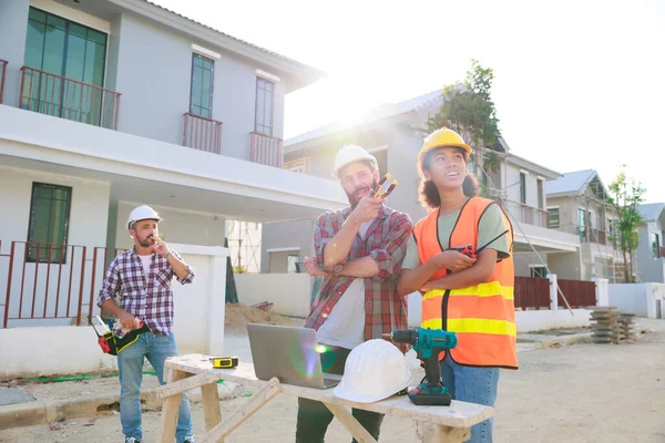 Takım dizüstü bilgisayarda çalışıyor. Profesyonel Makine Mühendisi Ekibi, inşaat sahasının altındaki imalat fabrikasında güvenlik kaskı takıyor..