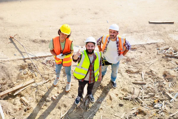 Üst görünüm çalışıyor. İnşaat alanındaki inşaat mühendisi ve inşaat ekibinin kendine güveni tam. Grup fotoğrafı. Birlik ve takım çalışması kavramı. 