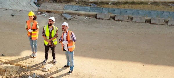 Üst görünüm çalışıyor. İnşaat alanındaki inşaat mühendisi ve inşaat ekibinin kendine güveni tam. Grup fotoğrafı. Birlik ve takım çalışması kavramı. 