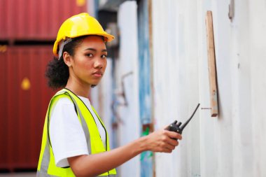 Zenci kadın liman işçisi konteynır kutusunu depo deposundan yüklüyor. Denizci ve uçak sigortası konsepti. Lojistik nakliye sahasında kargo konteynırı kutusu