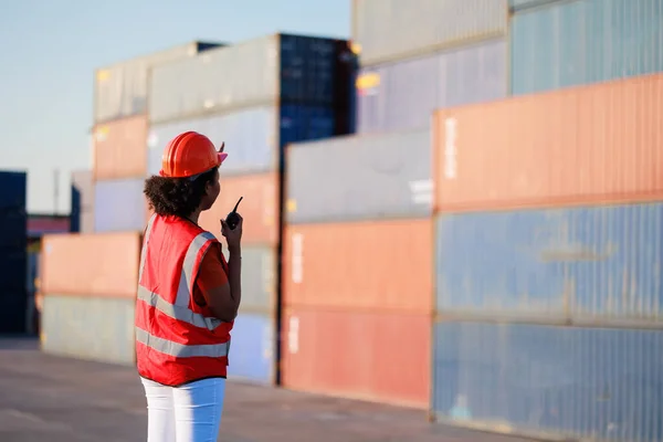 Back View Black Female Dock Worker Control Loading Containers Box lizenzfreie Stockfotos