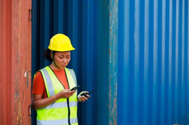 Çevrimiçi akıllı telefonla çalışıyor. Zenci kadın liman işçisi konteynır kutusunu depo deposundan yüklüyor. Denizci ve uçak sigortası konsepti. lojistik nakliye deposu