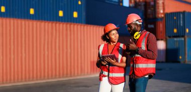 Portriat handsome male African American Industrial and female cock warehouse specialist. Black man worker wearing yellow protective hard hat helmet working at container yard.