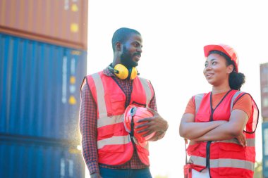 Portriat handsome male African American Industrial and female cock warehouse specialist. Black man worker wearing yellow protective hard hat helmet working at container yard.