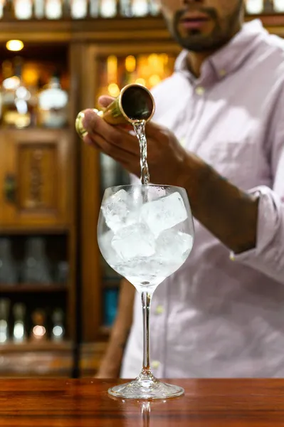 Les mains versant un cocktail dans un verre avec de la glace. — Photo