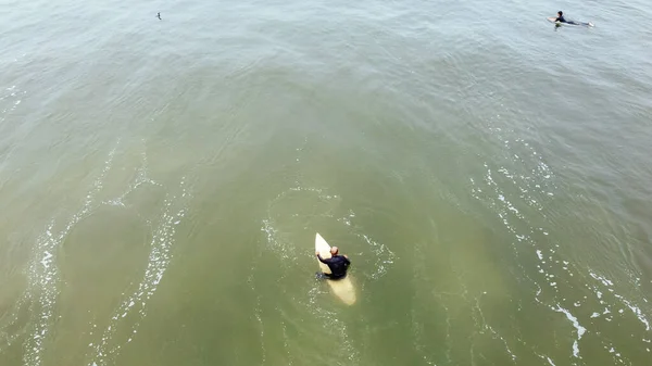 Homem maduro remando, deitado em uma prancha de surf - Homem sênior esportivo surfando no oceano Pacífico, em um dia ensolarado com céu azul e ondas transparentes. — Fotografia de Stock