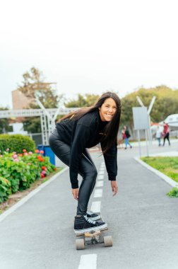 Young girl on longboard smiling. Outdoors, lifestyle.