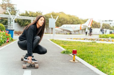 Young girl on longboard smiling. Outdoors, lifestyle.