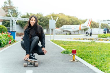 Young girl on longboard smiling. Outdoors, lifestyle.