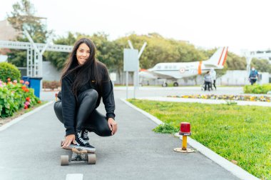 Young girl on longboard smiling. Outdoors, lifestyle.