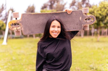 Young girl on longboard smiling. Outdoors, lifestyle.