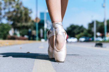 The feet of a Peruvian ballet dancer on an asphalt floor in the street.