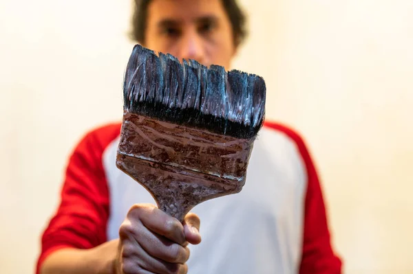 Close-up of professional house painter holding dirty paintbrush. — Stockfoto