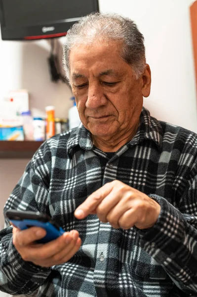 Happy senior Caucasian man looking at cellphone screen browse wireless internet. Smiling modern mature 70s grandfather text or message on smartphone. Elderly use cell technologies at home. Лицензионные Стоковые Изображения