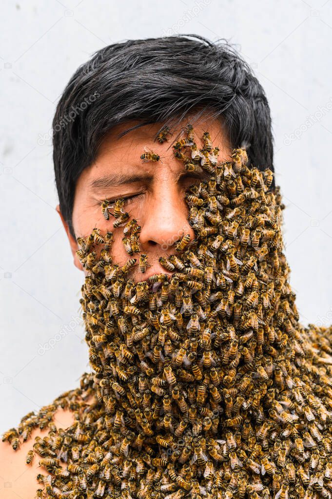Mans face covered by bees.