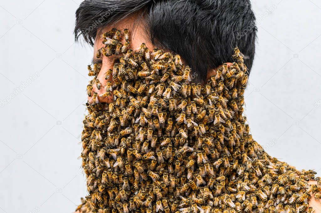 Mans face covered by bees.